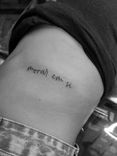 Tatuagem minimalista feita em linha fina (fineline) na região das costelas, com a frase "morar em si".