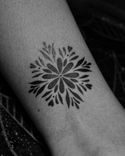 Tatuagem feita em pontilhismo (dotwork) na região do panturrilha, representando uma flor/mandala.