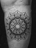 Tatuagem feita em pontilhismo (dotwork) e linha fina (fineline) na região da panturrilha, representando uma flor/mandala.