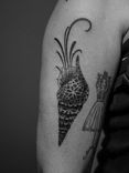 Tatuagem minimalista feita em pontilhismo (dotwork) na região do braço, representando uma concha do mar, preenchida com padrões geométricos.