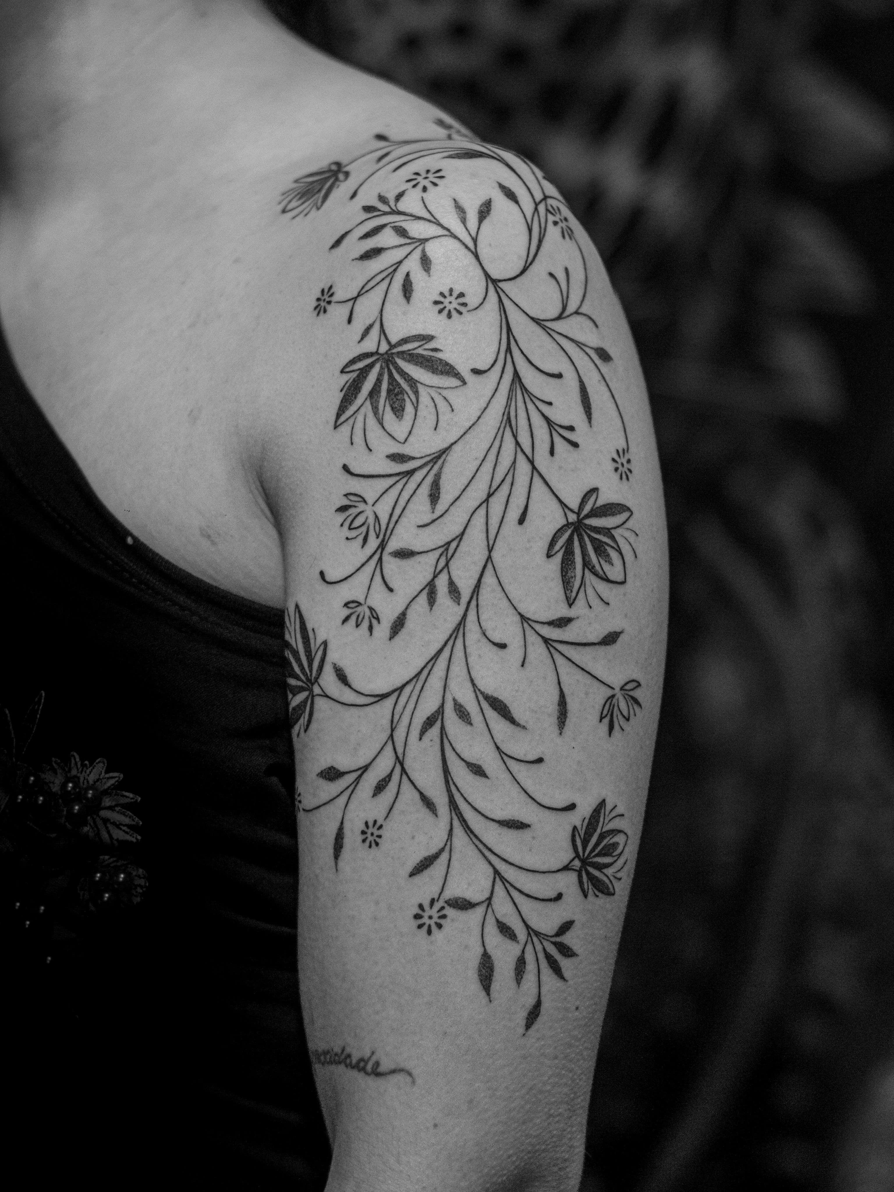 Tatuagem ornamental minimalista feita em linha fina (fineline) e pontilhismo (dotwork) na região do braço, representando uma flores mandalas.