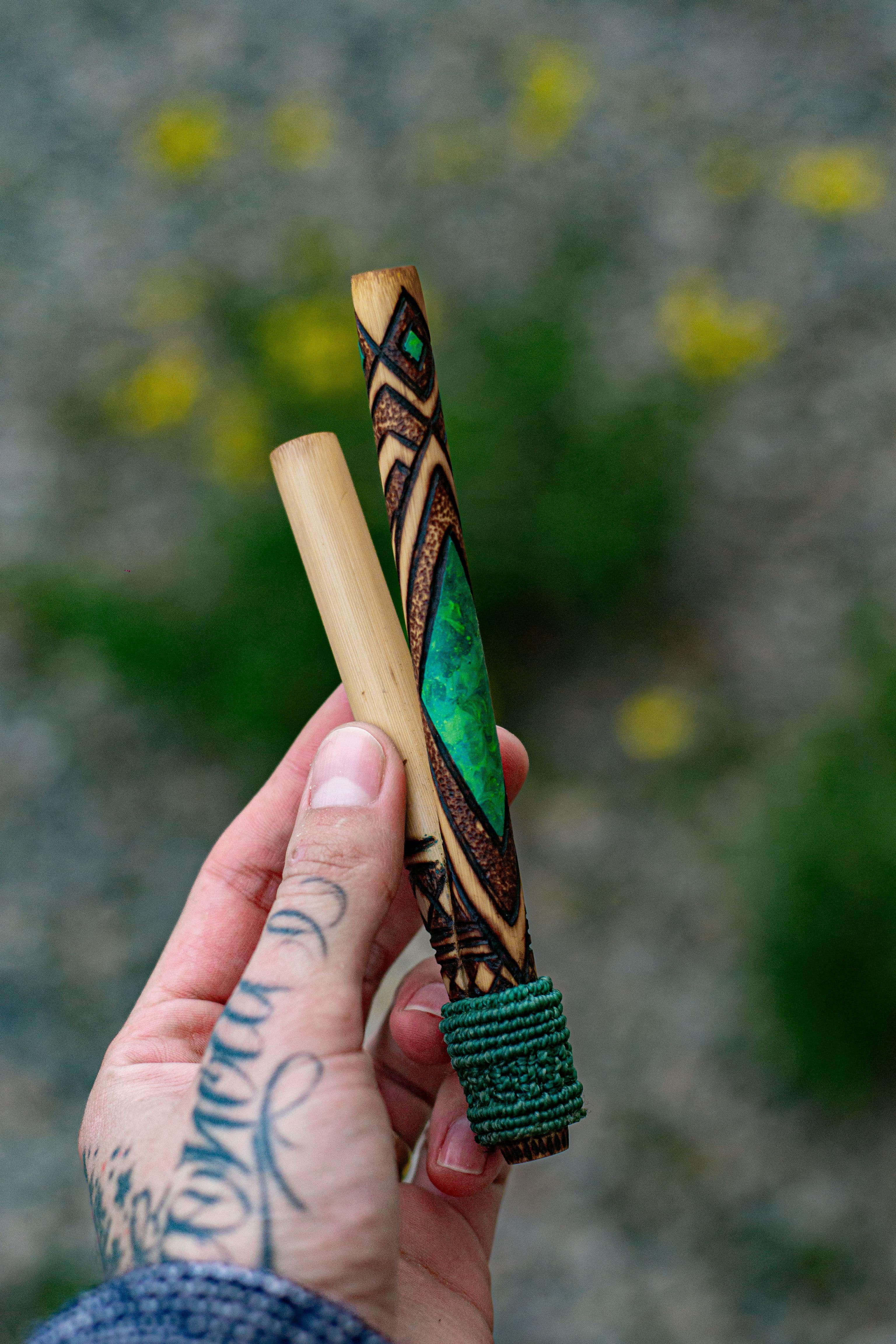 Kuripe artesanal feito em bambu natural, com acabamento em pirogravura autoral e pintura central em pigmento verde reativo à luz UV. A base traz um trançado em macramê, que oferece mais firmeza e conforto no uso.