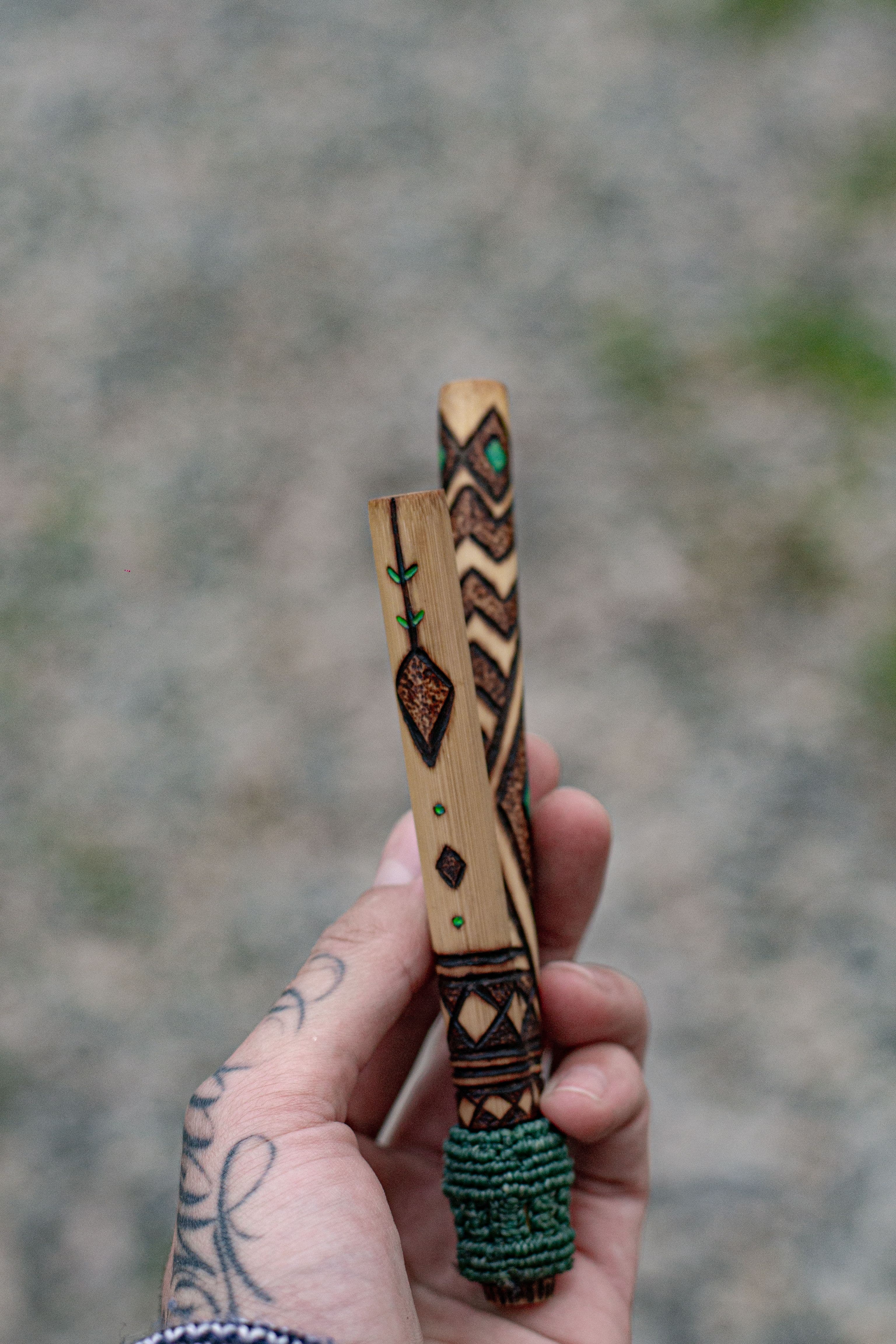 Kuripe artesanal feito em bambu natural, com acabamento em pirogravura autoral e pintura central em pigmento verde reativo à luz UV. A base traz um trançado em macramê, que oferece mais firmeza e conforto no uso.