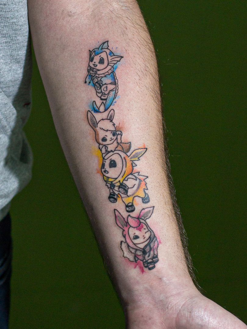 Tatuagem minimalista feita em linha fina (fineline), colorida, representando o pokemon "Evvee".
