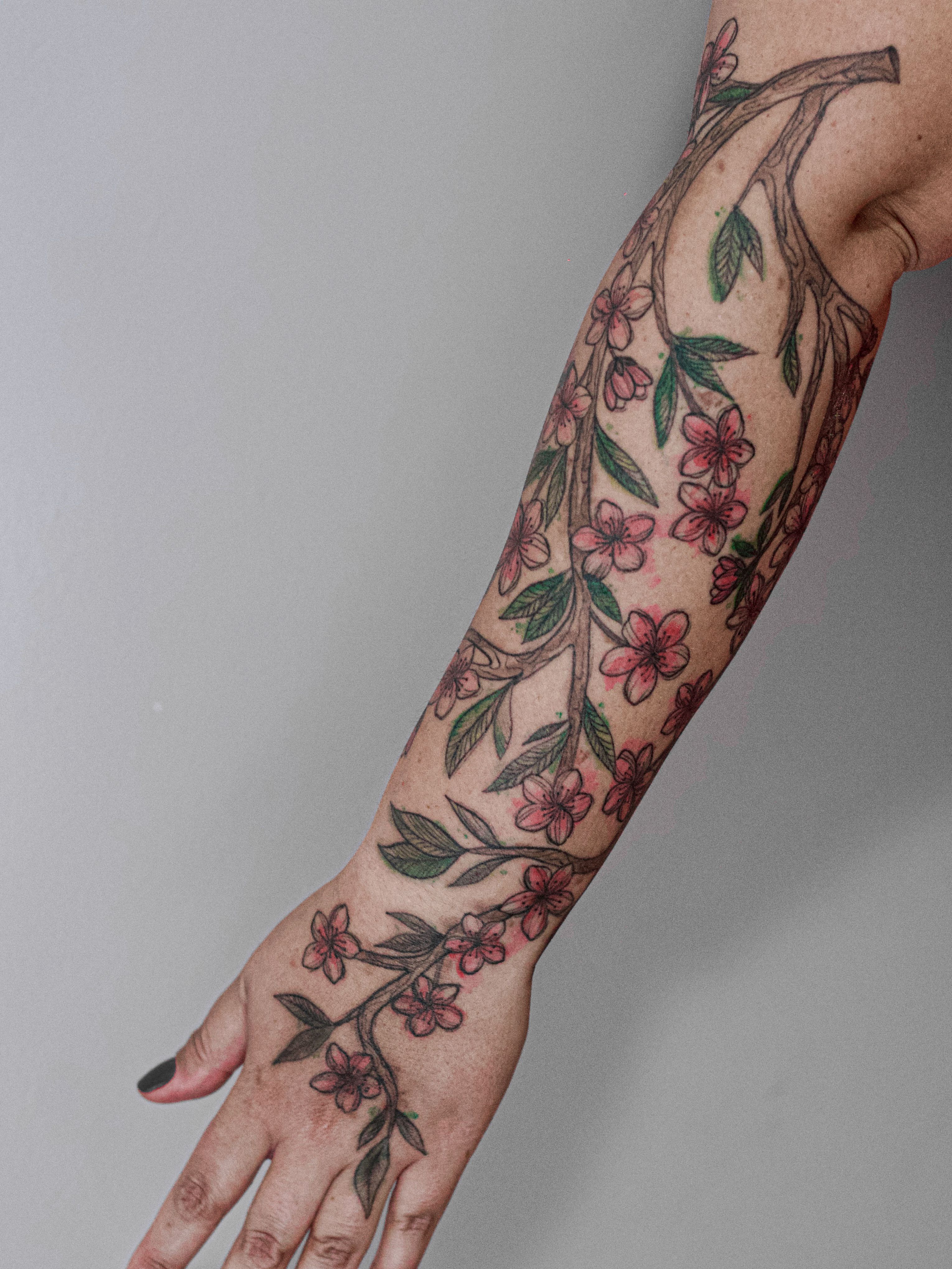 Tatuagem feita em linha fina (fineline), colorida estilo aquarela (watercolor), estilo esboço (sketch), representando um ramo de pintagueira.